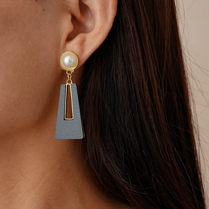 Détail de boucles d'oreilles géométriques avec perle et pendentif trapèze gris