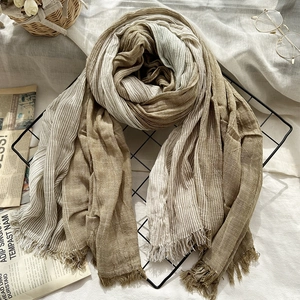 Artistic striped cotton linen scarf with tassels and natural crinkle texture on metal rack