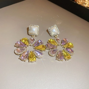 Detail of flower earrings with yellow and purple crystals and square pearl studs