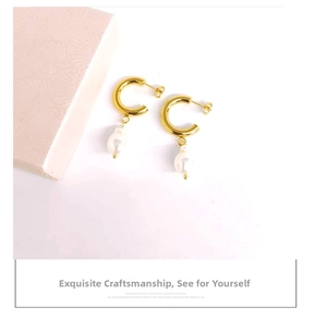 Detail of 18K gold stainless steel C-shaped earring with baroque pearl on pink jewelry box