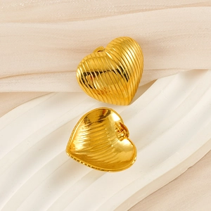 Close-up of golden heart earrings with vertical stripes on elegant white plaster tray
