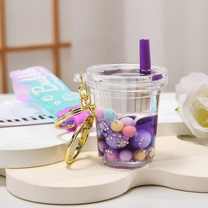 Portachiavi bubble tea viola in acrilico con sabbie mobili e anello dorato su base bianca