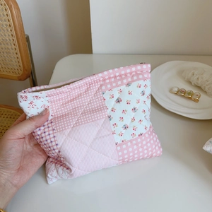 Close-up of pink floral quilted makeup bag with gold zipper and patchwork detail