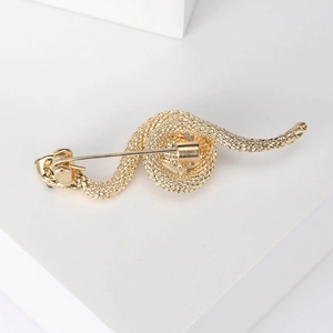 Vintage cobra brooch in gold finish with detailed scale texture on white stand