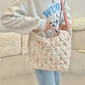 Detailed quilted texture of a white canvas crossbody bag with pink rabbit patterns