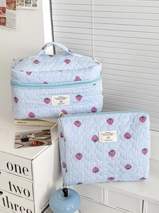 Close-up of quilted blue stripe toiletry bag with red strawberry pattern and handle