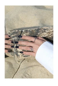 Artistic close-up of S925 sterling silver olive branch ring on beach rock background