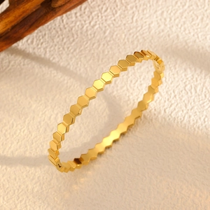 Détail macro du motif nid d'abeille doré sur le bracelet ondulé en acier titane