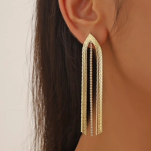 Macro shot of gold long tassel earrings with snake chains and sparkling rhinestones