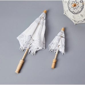 Macro shot of two white bridal lace umbrellas with natural wood handles in different sizes