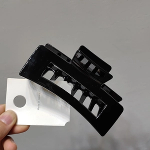 Close-up of large black geometric shark hair claw clip made of high-gloss acrylic material
