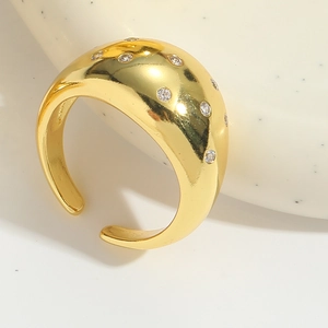 Detail of a wide gold-plated open ring with scattered diamonds on a ceramic tray