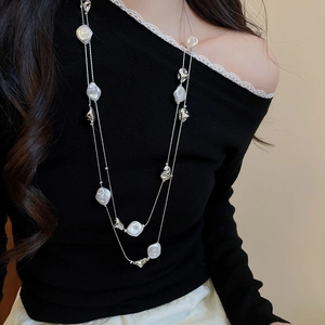 Detail of double-layer silver chain necklace with baroque pearls on a model wearing black