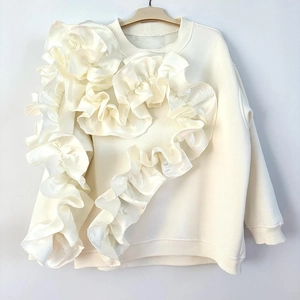 Détail de l'applique coeur à volants élégante sur un sweat blanc crème à manches longues