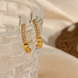Dettaglio orecchini a cerchio dorati 18K con zirconi micro-pave su bordo di vetro