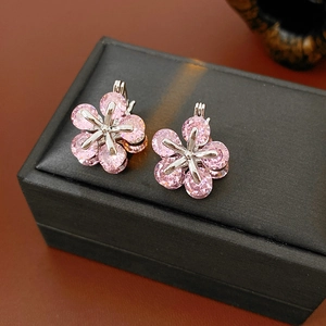 Vue macro des boucles d'oreilles fleur en argent avec pétales roses sur écrin noir