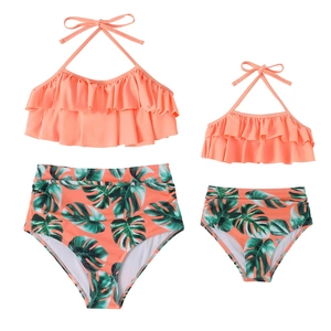 Matching two-piece family swimwear with coral ruffles and tropical leaf print