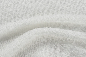 Macro shot of off-white textured knit fabric with soft boucle loop yarn finish