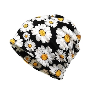 Slouchy beanie hat featuring white daisy prints on soft black knit fabric for women and men