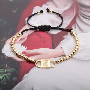 Gold braided bracelet with zircon inlaid letter G pendant on fashion background