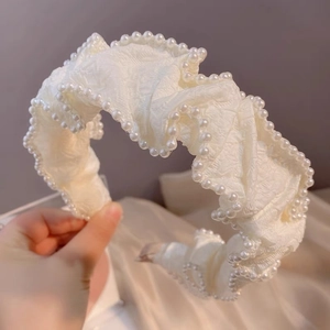 Gros plan du serre-tête en dentelle blanche avec perles élégantes et tissu texturé