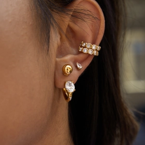 Elegant gold titanium earrings with sparkling zircons worn by a model in a close-up shot