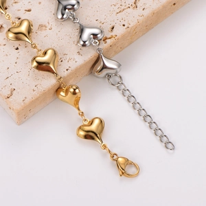 Elegant gold and silver stainless steel hollow heart link bracelet on stone background