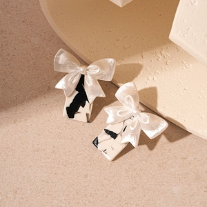 Elegant bow knot earrings with monochrome cow pattern on textured resin stud design