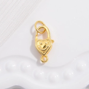Macro detail of gold-plated S925 silver heart lobster clasp with smiley face engraving