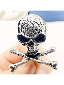 Close-up of vintage silver skull and crossbones brooch with black enamel gothic details