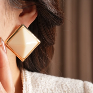 Close-up of geometric resin square stud earrings with gold metal trim on model