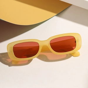 Minimalist Y2K style folding sunglasses with yellow translucent frame and orange lenses