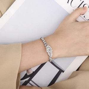 Close-up of a silver beaded Hamsa Hand charm bracelet worn on a female wrist