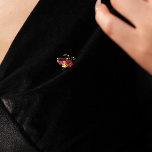 Macro view of a vintage enamel bee brooch with red gemstone wings on black velvet