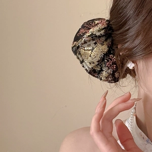 Close-up of handmade floral embroidery with gold threads on a black satin hair stick