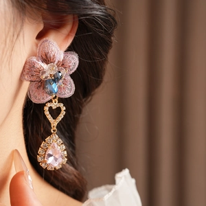 Close-up of pink embroidered flower earring with crystal tassels on a female model