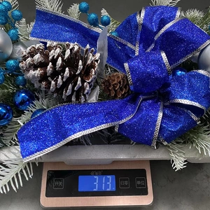 Christmas blue glitter bow decoration with pine cones and berries weighing 313g on a scale