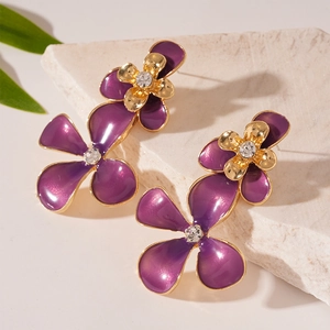 Retro purple flower drop earrings with crystals and gold finish on natural stone background