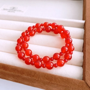 Detailed macro view of red agate beads double-layer bracelet in a brown velvet jewelry box