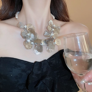 Detailed shot of a floral metal necklace with white pearls on a model wearing black