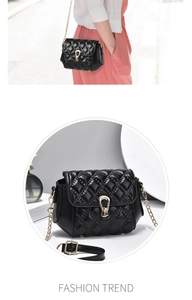 Detail of black quilted shoulder bag with gold metal buckle and elegant chain strap