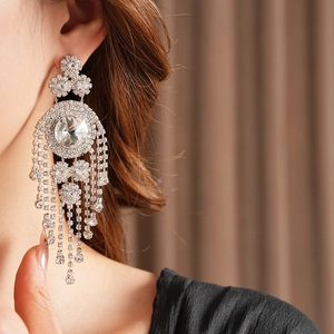 Dettaglio di orecchini a nappa con strass argentati in stile vintage indossati da modella