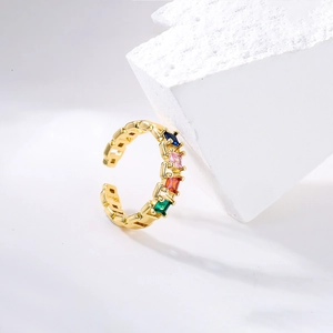 Detail of gold open ring featuring colorful square-cut zircons on a white backdrop