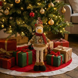 Detail of Christmas duck plush toy in plaid sweater standing by festive Christmas tree