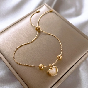 Elegant gold heart pendant bracelet with opal inlay on a premium brushed metal jewelry box