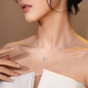 Elegant silver heart necklace with crystal inlay worn by model in a soft lighting