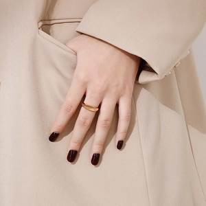 Detail of a minimalist gold ring with an oval cat-eye gemstone on a model's hand