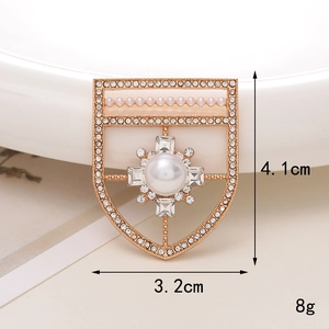Detailed view of a gold shield brooch with large pearl and crystals, size 4.1cm x 3.2cm