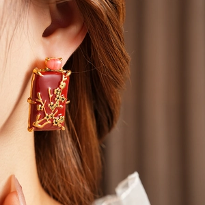 Gros plan de boucles d'oreilles carrées vintage émaillées rouges avec motifs floraux