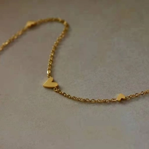 Elegant gold titanium necklace featuring minimalist heart-shaped charms and fine chain link